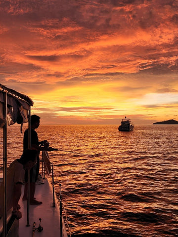 Party Boat Kota Kinabalu under a large waterfall with warm light