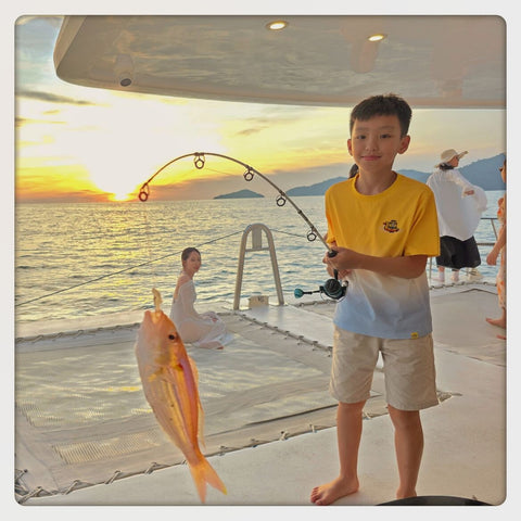 Child holding a fish on a Party Boat Kota Kinabalu at sunset
