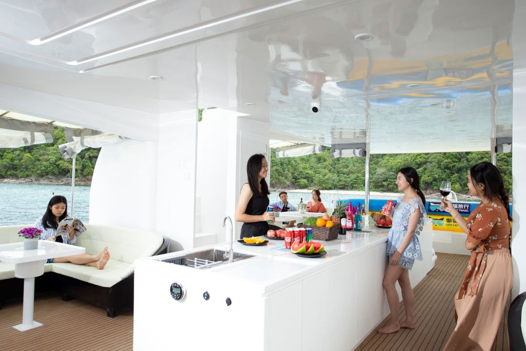 People enjoying a meal on a Party Boat Kota Kinabalu with a modern kitchen setup.