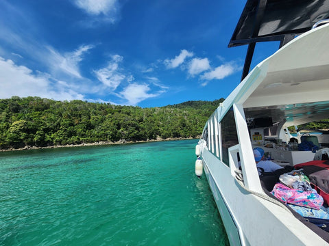 Snowy Yacht cruising near Gaya Island in Kota Kinabalu, Sabah, surrounded by clear turquoise water and lush tropical rainforest scenery.