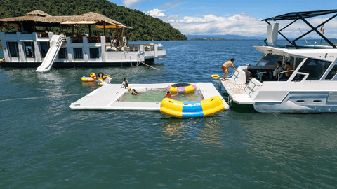 Snowy Yacht anchored beside the Floating Club House in Kota Kinabalu, with guests enjoying inflatable pool toys and water activities under clear blue skies.