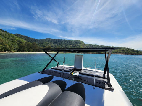 Front deck of the Snowy Yacht cruising near Gaya Island, Kota Kinabalu, surrounded by turquoise sea and lush tropical hills under a clear blue sky.
