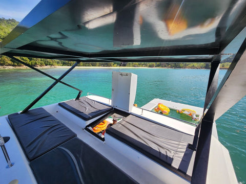 Upper deck of the Snowy Yacht in Kota Kinabalu with cushioned lounge seats overlooking turquoise waters and a tropical island shoreline.