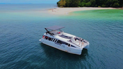 Snowy Yacht anchored near a pristine beach in Kota Kinabalu, surrounded by turquoise blue waters and lush green island scenery